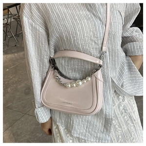Détail du sac sous l'aisselle en cuir verni rose clair avec perles et chaîne argent