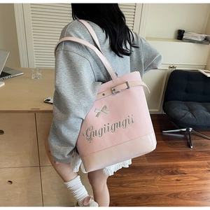 Grand sac cabas rose avec nœud argenté et logo métallique, vue latérale sur l'épaule