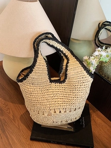Large capacity straw tote bag with black trim and hollowed base on a table