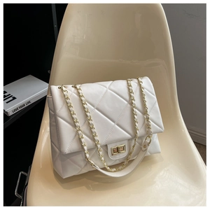 Detailed view of white quilted leather texture and golden metal chain strap on a bag