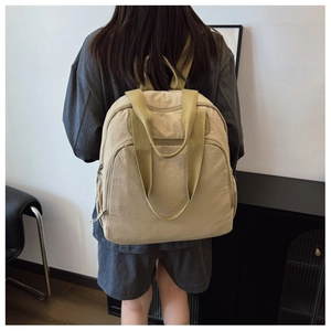 Detalle de mochila beige multifuncional con correas anchas y compartimentos grandes