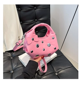 Sac à main rose demi-lune avec nœud et clous argentés sur fond en cuir noir élégant