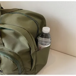 Detailed view of the army green travel backpack side pocket holding a water bottle