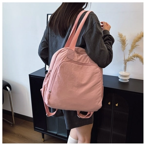 Detalle de mochila de nailon rosa con amplio bolsillo frontal y correas de tejido
