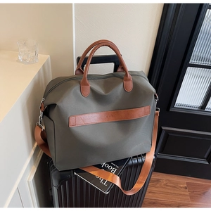 Gros plan du sac fourre-tout en toile olive avec anses en cuir sur une valise