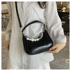 Détail du sac dumpling en cuir noir avec décor perlé et accents de chaîne argentée