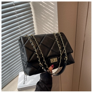 Close-up of black quilted leather with gold metal twist lock and chain strap detail