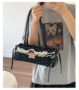 Détail du sac à main à pois noirs et blancs avec bordure en dentelle et nœud en velours