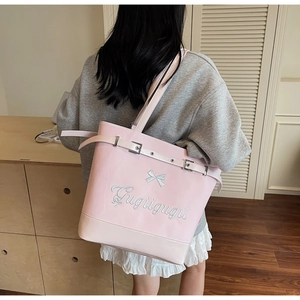 Détail d'un sac cabas rose brillant avec broderie nœud et sangle à boucle élégante