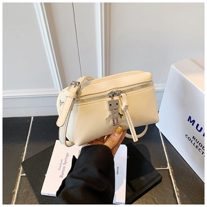 Detail view of beige mini crossbody box bag with silver robot charm and metal zipper