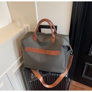 Détail du sac fourre-tout en toile olive avec anses en cuir sur une valise