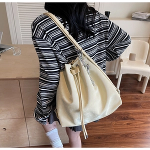 Fashionable cream bucket bag shown as a backpack on a model in a minimalist room