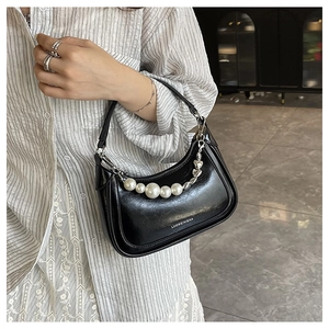 Gros plan du sac croissant noir brillant avec chaîne décorative en perles et cœurs