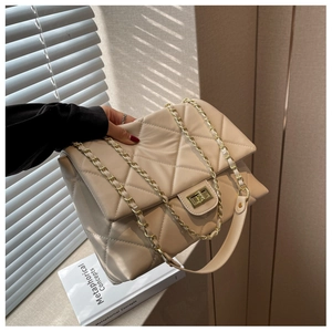 Detail of beige quilted flap bag with light gold metal lock and chain shoulder strap