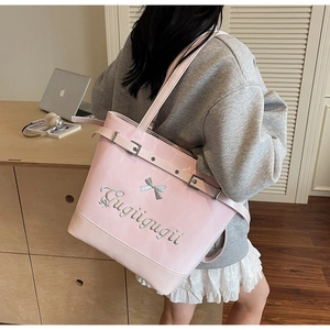 Gros plan du sac cabas rose brillant avec détail de nœud argenté et broderie chic