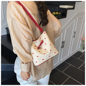Detail of cream shoulder bag with red bow prints and golden heart charm detail