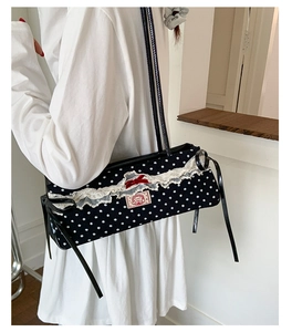 Détail d'un sac bandoulière à pois avec dentelle blanche et un petit nœud rouge