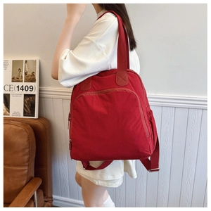 Detalle de una gran mochila minimalista de nailon rojo para mujer en un ambiente