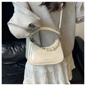 Detail of cream white half-moon bag with elegant large pearl chain and silver hardware