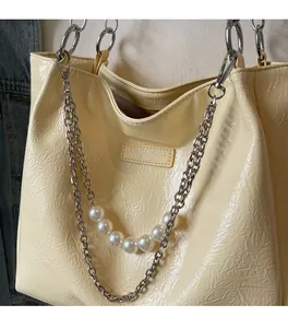 Detail of beige tote bag with wrinkled texture, silver chain and pearl decoration