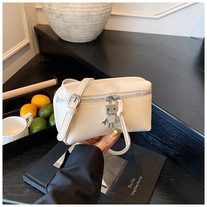 Detail of cream mini crossbody bag featuring a unique silver robot charm pendant
