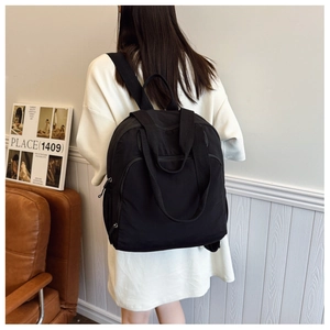 Vista trasera de una mochila minimalista de nailon negro usada por una modelo en interior