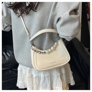 Detail of a chic cream crescent bag with a pearl heart chain and long strap