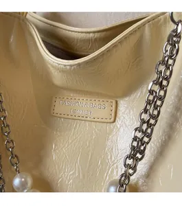 Detail of beige wrinkled leather tote with silver chain, pearl decor and fashion tag