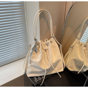 Detail of cream white bucket bag featuring drawstring closure and silver heart charm