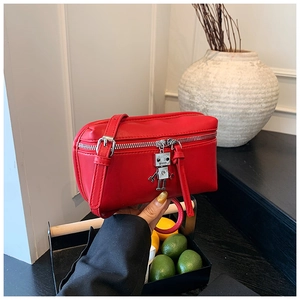 Detailed shot of red textured leather mini bag with silver robot charm and metal zipper