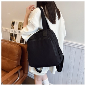 Detalle de mochila de nailon negro con hebillas plateadas y compartimento con cremallera