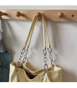 Detail of cream tote bag featuring pleated texture and leather metal chain shoulder strap