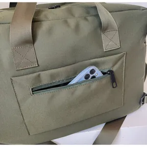 Detail view of the side zipper pocket on a green canvas travel bag holding a smartphone