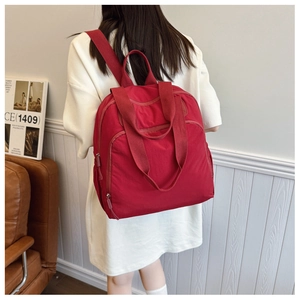 Vista posterior de una modelo con la mochila de nailon roja en un entorno interior minimalista
