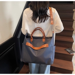 Détail du grand sac cabas en nylon bleu marine avec anses en cuir marron porté