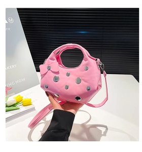 Détail d'un sac à main en cuir verni rose avec rivets argentés et nœud décoratif chic
