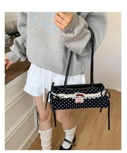 Détail d'un sac à bandoulière rétro à pois avec dentelle blanche et petit nœud rouge
