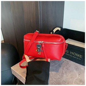 Close-up of red mini crossbody bag with a unique robot charm and silver zipper detail