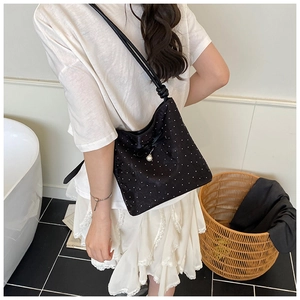 Detail of black bow shoulder bag with white polka dots and elegant pearl pendant