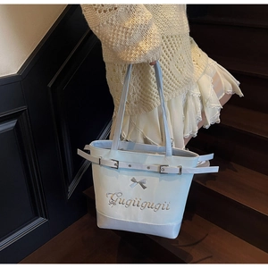 Détail du grand sac cabas bleu clair avec nœud, broderie et boucles latérales sur mannequin