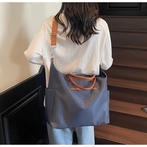 Vue arrière d'un mannequin portant un grand sac cabas en toile bleu gris à anses brunes