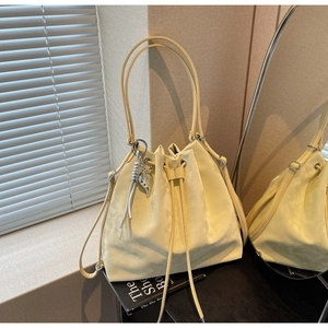 Detail of light yellow suede bucket bag with drawstring closure and silver star charm