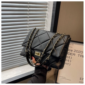 Detailed view of the diamond quilted texture and gold metal twist lock on the crossbody bag