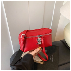 Close-up of a red leather mini crossbody bag with a unique silver robot charm detail
