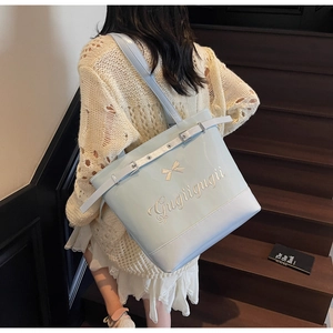 Détail du sac cabas bleu et blanc avec breloque nœud en métal et broderie Gugiigugii