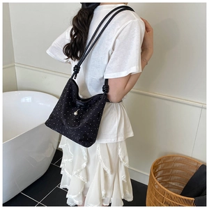 Chic black polka dot underarm bag with white pearl pendant detail on fabric texture