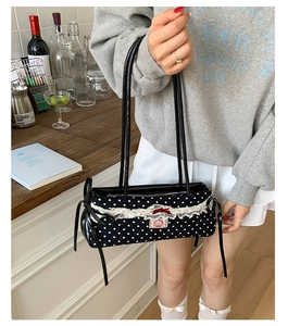 Détail du sac à pois avec bordure en dentelle blanche et nœuds rouges dans un décor de style
