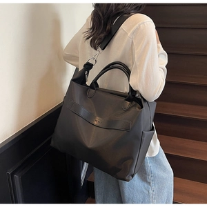 Gros plan d'un grand sac cabas noir en nylon avec bandoulière réglable sur modèle