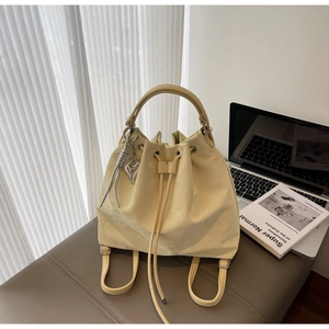 Beige bucket bag on brown stool with laptop and book in minimalist interior