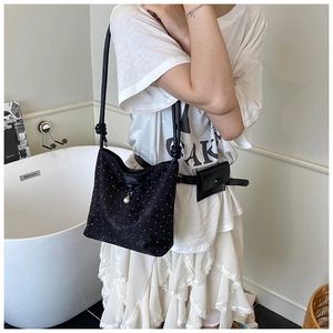 Polka dot bucket bag with bow and pearl detail shown styled in a fashion outfit